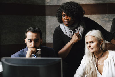 Confident law experts discussing over computer during meeting at office