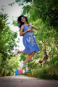 Portrait of young woman standing against trees