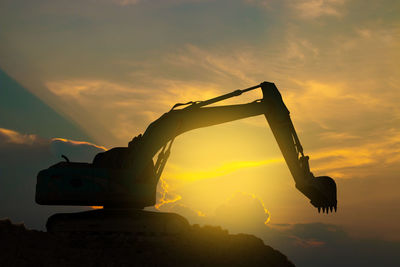 Low angle view of silhouette crane against sky during sunset