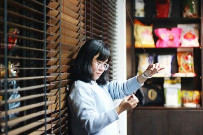 Woman standing by window blinds