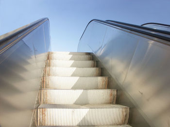 Closeup of exterior escalator viewed upwards with clear blue sky in the background