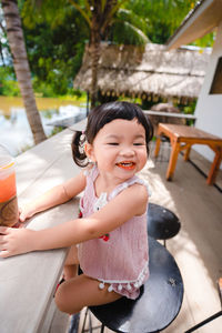 Cute girl sitting on woman looking at camera