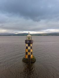 Lighthouse on beach against sky