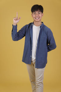 Portrait of smiling boy standing against yellow background