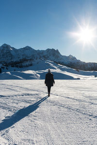 Rear view of woman walking on snowcapped field during winter