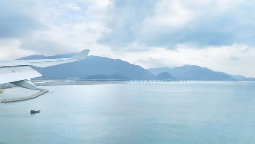 Scenic view of sea by mountains against sky