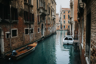 Boats on canal amidst buildings in city