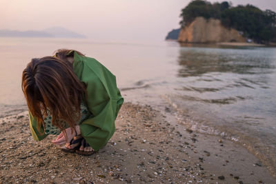 Close-up of woman looking at sand on beach