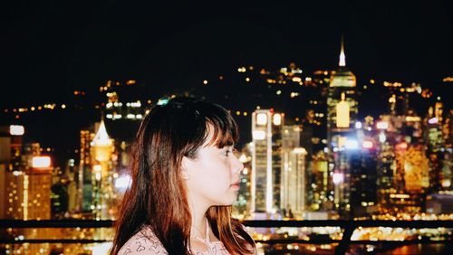 Profile view of woman against illuminated city at night