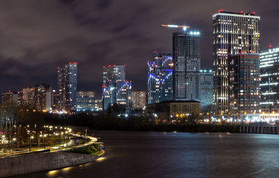 Illuminated city at waterfront at night
