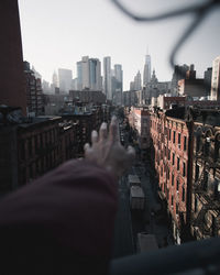 Cropped hand of person against buildings in city
