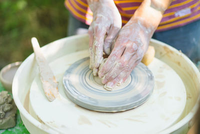 Potter making a clay object on pottery wheel in outdoors. 