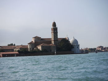 View of buildings by sea against sky in city