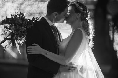 Newlywed bridegroom kissing outdoors