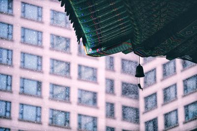 Low angle view of bell hanging on roof during snowfall