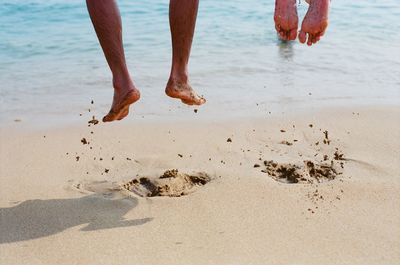 Low section of people jumping on shore at beach