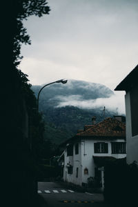 House by road amidst buildings against sky