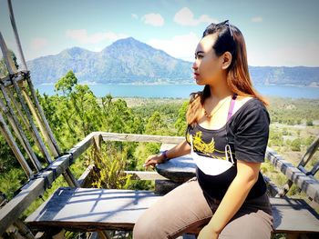 Young woman sitting on seat against mountains