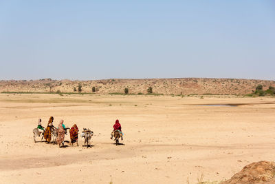 Man riding motorcycle on desert against clear sky