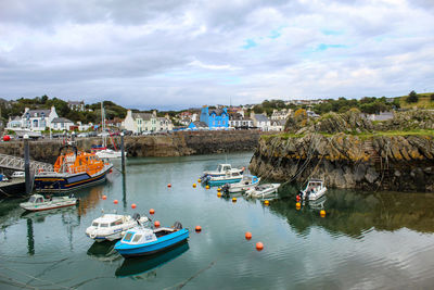 Boats moored in sea by buildings against sky