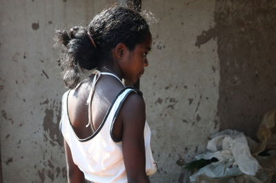 Side view of girl standing against wall