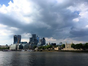 City at waterfront against cloudy sky