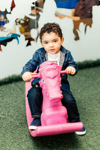 Portrait of smiling boy sitting on rocking horse