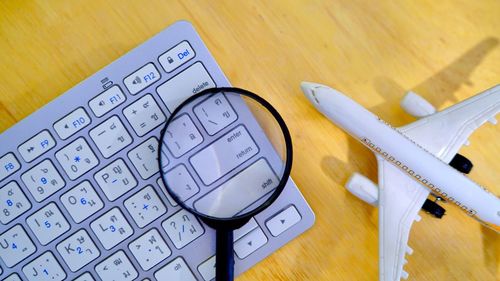 Magnifying glass with computer keyboard and model airplane on table