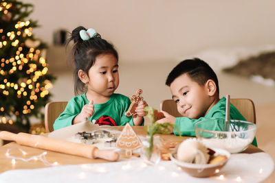 Asian kids brother and sister in pajamas prepare festive food for the christmas holiday at home