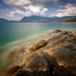 Scenic view of lake by mountains against sky