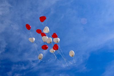 Low angle view of balloons flying against blue sky