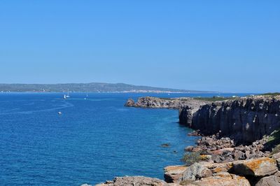 Scenic view of cliffs and sea against clear blue sky