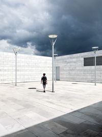 Man in front of building against cloudy sky