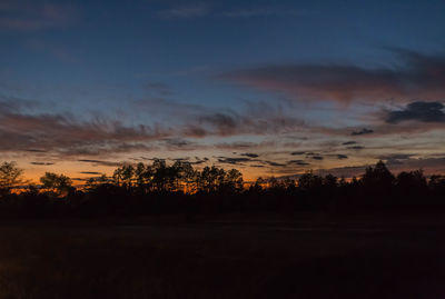 Silhouette trees on landscape against sky at sunset