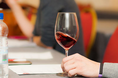 Cropped hand having red wine at table