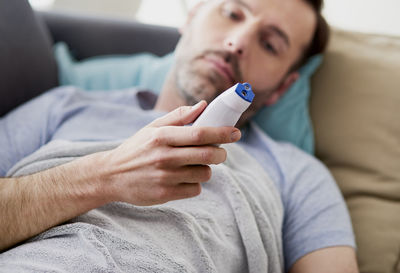 Midsection of man using mobile phone while sitting on sofa