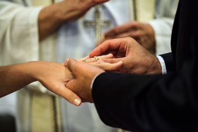 Groom putting ring on bride finger at wedding ceremony