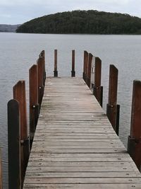 Wooden jetty on pier over lake against sky