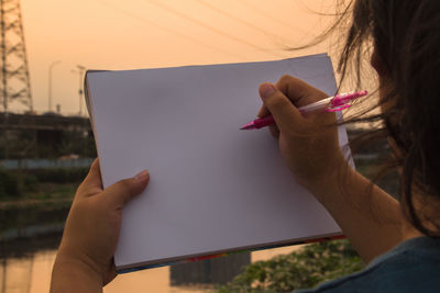 Midsection of woman holding smart phone on paper