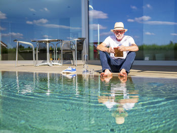 Senior man reading e-book at swimming pool