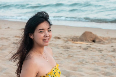 Portrait of young woman standing at beach