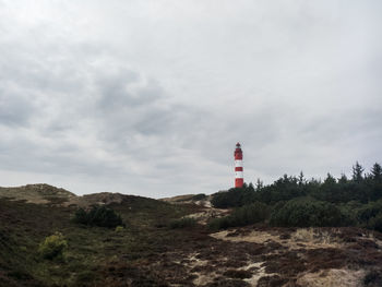 Lighthouse by road amidst buildings against sky