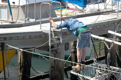 Full length of man standing by footbridge at harbor over sea