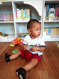 Boy sitting on book at home