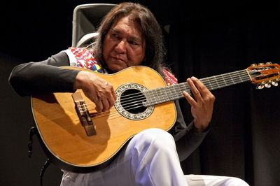 Man playing guitar while sitting on seat