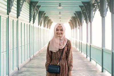 Portrait of smiling young woman standing on railing