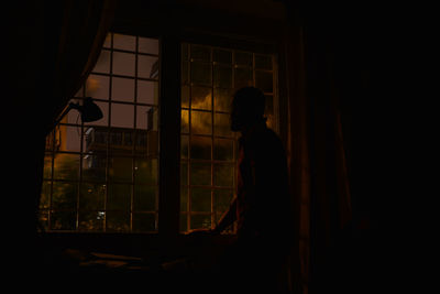 Silhouette of man standing on window