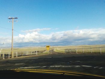 Empty road against cloudy sky