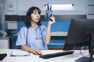 Portrait of young woman using mobile phone in office