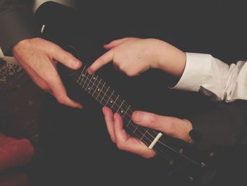 Cropped hands of father with child playing guitar